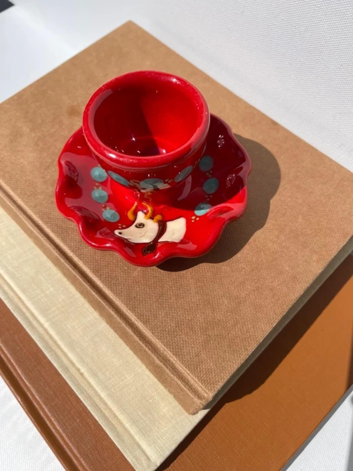 Handpainted studio pottery red waved egg cup with cow motif
