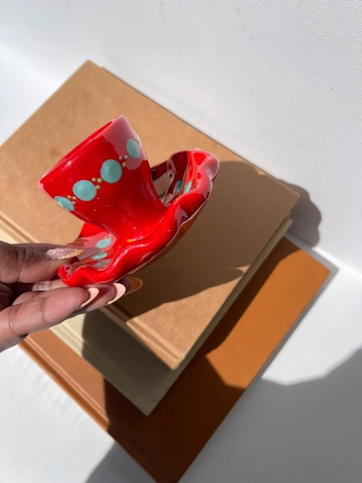 Handpainted studio pottery red waved egg cup with cow motif