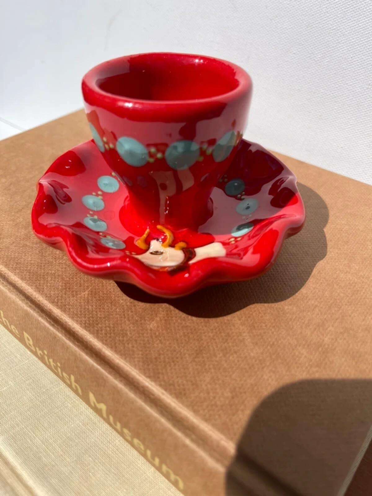Handpainted studio pottery red waved egg cup with cow motif